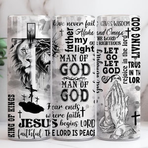 May include: Three tall, cylindrical tumblers with religious themes. One features a lion's head and cross, another has text including "Man of God", and the third shows praying hands. The tumblers are decorated with black and white graphics and text.