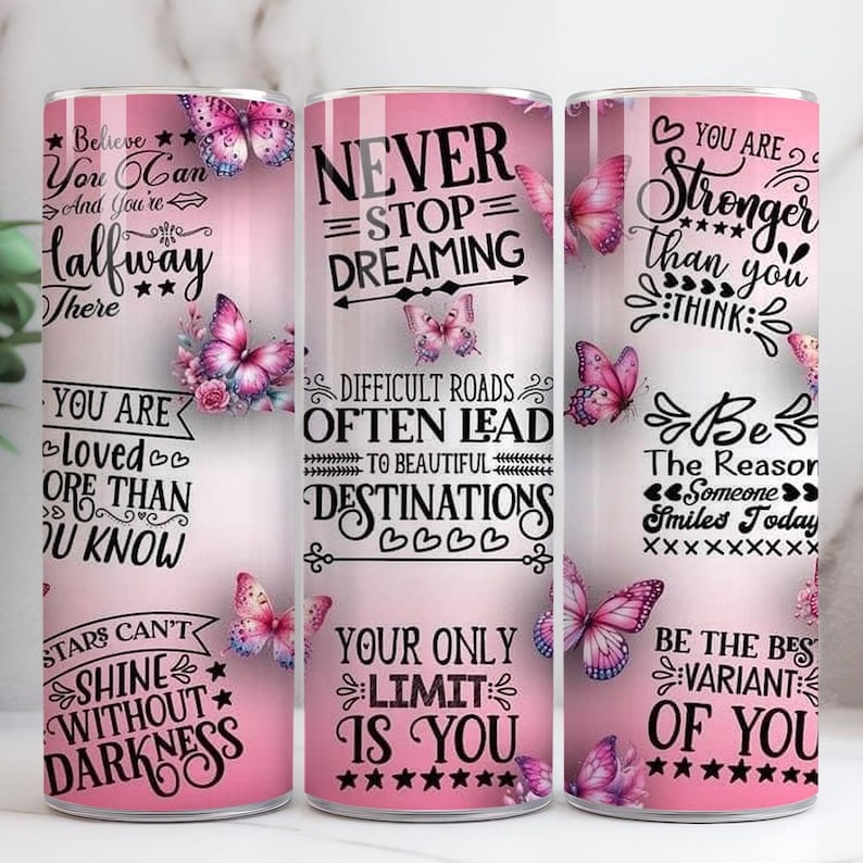 May include: Three pink tumblers with motivational quotes and butterfly designs. The tumblers display phrases such as "Believe You Can," "Never Stop Dreaming," and "You Are Stronger." Each tumbler has a unique design with black text and pink accents.