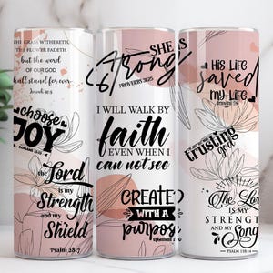 May include: Three white tumblers with floral designs and inspirational quotes in black script. The quotes include "Choose Joy," "She is Strong," and "His Life Saved." The tumblers have a pink and white colour scheme.