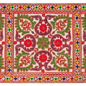Könnte beinhalten: Bestickter Textil mit einem sich wiederholenden Blumenmuster in Rot, Grün und Lila auf cremefarbenem Hintergrund. Das Design zeigt stilisierte Blumen und Blätter, umrahmt von einem Rand aus bunten geometrischen Formen. Der Textil ist wahrscheinlich ein dekoratives Stück.