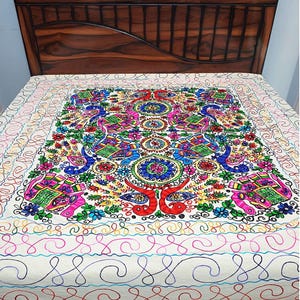 Peut inclure: Un couvre-lit blanc orné de broderies colorées faites à la main. Le motif central présente plusieurs éléphants, oiseaux et fleurs dans des tons vifs de rose, bleu, vert et rouge, entourés de motifs de lignes entrelacées et sinueuses.