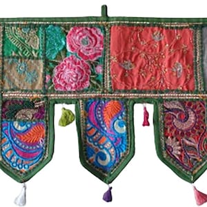 Könnte beinhalten: Ein dekorativer Wandbehang aus Textil mit grünem Rand und farbenfrohem Patchwork-Design. Der obere Bereich zeigt florale und geometrische Muster in Rosa-, Türkis- und Orangetönen. Der untere Bereich hat dekorative Quasten und Paisley-Muster.