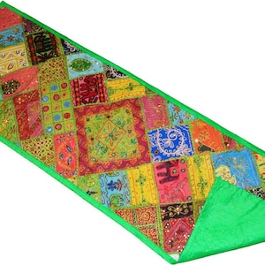 Puede incluir: Un camino de mesa rectangular con un diseño de patchwork vibrante de cuadrados de tela multicolores con bordados intrincados, lentejuelas y motivos de elefantes, acabado con un borde verde brillante y un reverso de tela verde a juego.