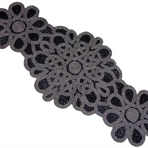 May include: A beaded table runner in a floral design. The runner is primarily dark gray with black accents, featuring a repeating pattern of interconnected loops and flower-like shapes. The beads create a textured surface.