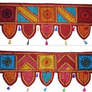 Può includere: Due colorate tende a vetro tessili ricamate. Ognuna presenta un design patchwork con quadrati e triangoli rossi, arancioni, gialli e blu, adornati con specchi e nappe. Le tende a vetro sono probabilmente per l'arredamento della casa.