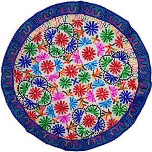 Puede incluir: Textil bordado circular con fondo blanco y un vibrante estampado floral. El diseño presenta flores rojas, azules, verdes y rosas, delineadas en negro, con un borde azul. El borde tiene un patrón bordado ondulado.