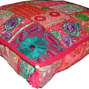 Puede incluir: Cojín de suelo cuadrado con un diseño de patchwork en tonos rosa, rojo y turquesa. El cojín presenta patrones florales bordados y está rematado con un borde y borlas de color rosa brillante. Un acento decorativo para la decoración del hogar.