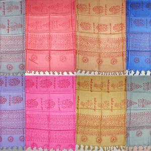 Può includere: Otto sciarpe fantasia in vari colori, tra cui rosa, blu e beige. Ogni sciarpa presenta un disegno ripetuto con testo e simboli e un bordo con frange. Le sciarpe sono esposte fianco a fianco.