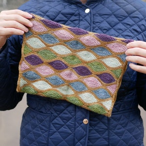 May include: A knitted scarf with a geometric pattern of leaves in shades of brown, green, purple, pink, and blue.