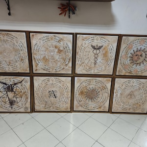 Peut inclure: Huit œuvres d'art carrées encadrées avec un aspect vintage et vieilli. Chaque pièce présente un motif circulaire central avec des symboles et du texte complexes, dans des tons beige et marron. Les cadres sont de couleur bois foncé, et le thème général suggère l'art ésotérique ou historique.