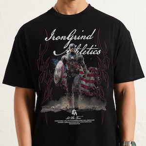 Puede incluir: Camiseta negra con un dise&ntilde;o de Capit&aacute;n Am&eacute;rica con su escudo y la bandera estadounidense. La camiseta tiene el texto "IronGrind Athletics" y "Sit The Tone", junto con un mensaje motivacional sobre el bienestar y la determinaci&oacute;n.