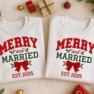 May include: Two white sweatshirts with the text "MERRY and MARRIED EST. 2025" in red and green. A red bow and holly accents the text. The sweatshirts are surrounded by Christmas decorations, including wrapped gifts and ornaments.