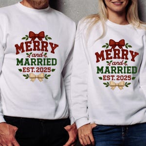 May include: White sweatshirts with the text "MERRY and MARRIED EST. 2025" in red and green, with a bow graphic. The sweatshirts are for a couple, perfect for a wedding or anniversary celebration.