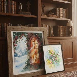 May include: Two framed watercolor paintings. One features a winter landscape with a snow-covered path and a warm, glowing window. The other displays a bouquet of flowers in shades of pink, yellow, and blue. The paintings are leaning against a wooden bookshelf.