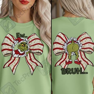 Puede incluir: Camiseta verde claro con un diseño temático de Grinch. La parte delantera muestra al Grinch en un lazo, con el texto "Ew..". La parte trasera muestra la parte trasera del Grinch en un lazo, con el texto "BRUH...". Los lazos tienen rayas rojas y blancas.
