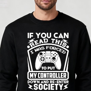 May include: Black sweatshirt with a white graphic. The graphic reads "IF YOU CAN READ THIS, I WAS FORCED TO PUT MY CONTROLLER DOWN AND RE-ENTER SOCIETY." The design includes a game controller.