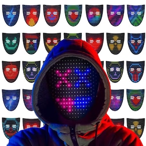 Puede incluir: Una persona con una máscara LED negra con un diseño pixelado colorido. La máscara está rodeada de varias máscaras LED con diferentes expresiones faciales. La persona lleva una sudadera con capucha.