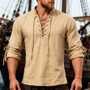 May include: A beige linen shirt with a lace-up neckline and long sleeves. The sleeves are gathered and tied at the cuffs. The shirt has a relaxed fit and a classic, rustic design.