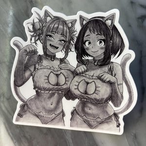 Puede incluir: Una pegatina en blanco y negro con dos personajes de estilo anime vestidos con trajes de gato. Los personajes sonr&iacute;en y llevan orejas y colas de gato. La pegatina tiene un borde blanco.