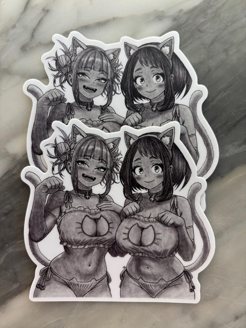 Puede incluir: Cuatro pegatinas en blanco y negro con ilustraciones de estilo anime de dos chicas con trajes de tem&aacute;tica felina. Cada chica tiene orejas de gato, un collar y una cola. Las pegatinas est&aacute;n sobre una superficie gris claro.