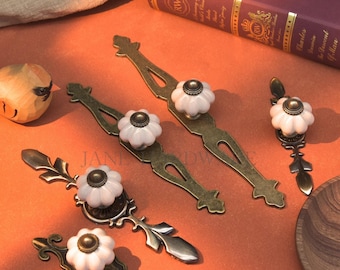 Ceramiczne uchwyty do szafek w kolorze postarzanego brązu: szaro-biała gałka z płytką, uchwyty do szuflad w stylu vintage