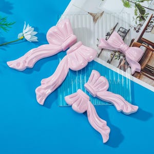 Könnte beinhalten: Ein Set aus drei Keramikbechern mit gesprenkelter, matter Oberfläche. Die Becher sind in Creme-, Hellgrau- und Dunkelgrautönen gehalten. Jeder Becher hat ein schlichtes, minimalistisches Design.