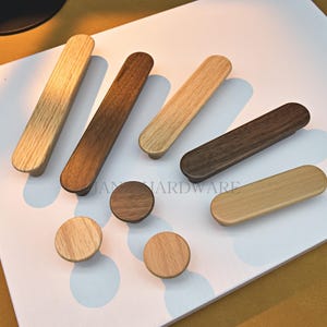May include: A selection of wooden cabinet handles and knobs. The handles are elongated, with a range of brown tones and a natural wood grain. The knobs are circular and also display a natural wood grain finish. Measurements are in centimetres.