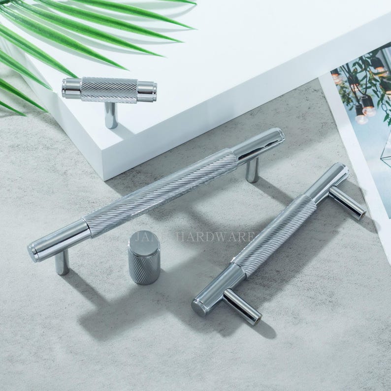 May include: A collection of polished chrome cabinet hardware, including bar pulls, T-knobs, and a cylindrical knob. The hardware features a textured, ridged design. The brand name "JAN HARDWARE" is visible on the surface.