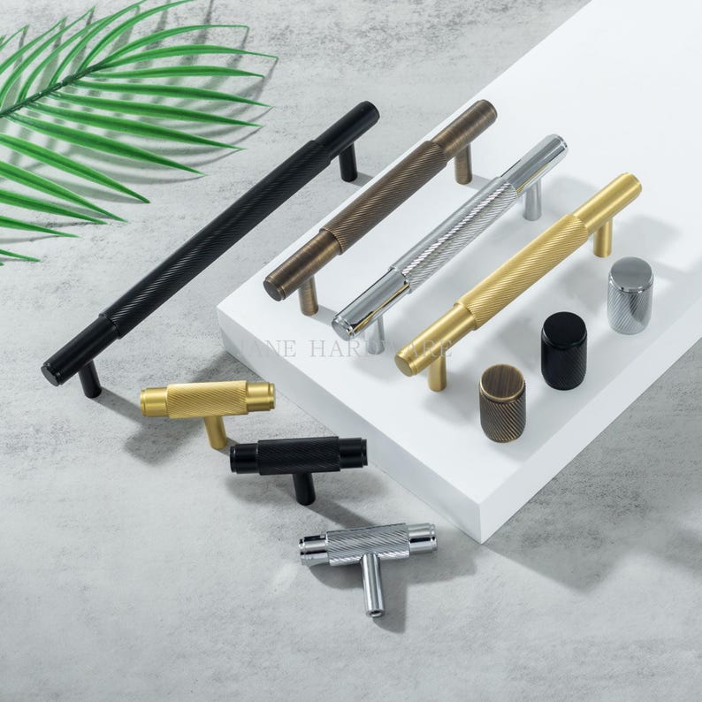 May include: A collection of various metal cabinet hardware, including handles and knobs. The handles come in black, bronze, silver, and gold finishes, with textured and smooth designs. The knobs are cylindrical and also feature textured surfaces.