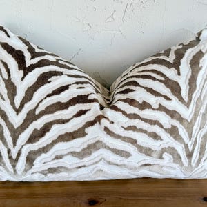 May include: A white and brown zebra patterned throw pillow with a soft, plush texture.