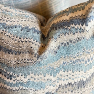 May include: Close-up of a blue and beige patterned pillow with a wavy design.