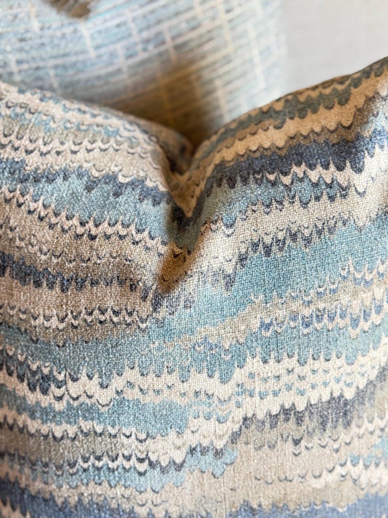May include: Close-up of a blue and beige patterned pillow with a wavy design.