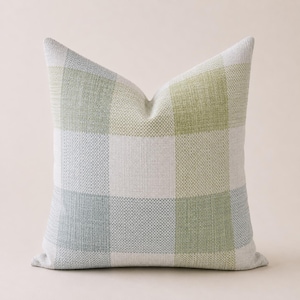 May include: Square throw pillow with a woven checkered pattern in shades of green, white, and light blue. The pillow has a soft, textured appearance and a neutral background. The pillow is designed for home decor.