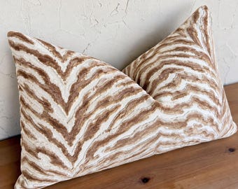 May include: A rectangular throw pillow featuring a textured, raised pattern of wavy, organic lines in shades of tan and brown against a cream-colored background. The fabric has a distinct, tactile surface with a repeating abstract design.