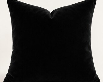May include: A square throw pillow cover made of solid black velvet fabric. The pillow features a soft, plush texture with a slight sheen and a classic knife-edge finish, presenting a uniform and deep black color across the entire surface.