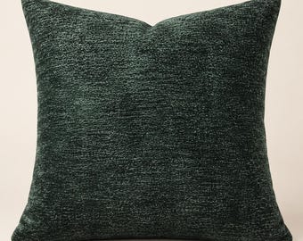 May include: A square throw pillow featuring a deep forest green color with a textured, woven fabric surface. The pillow has a consistent, dense appearance with subtle variations in the dark green threads, creating a soft, matte finish.