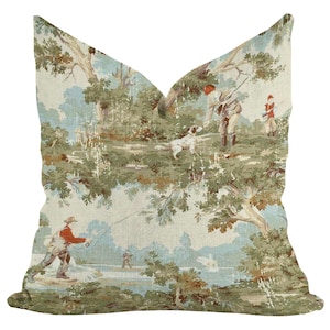 May include: Square cushion featuring a pastoral scene with figures fishing and hunting. The design has a light blue and green colour palette, with a detailed illustration of trees and figures. The cushion is square shaped.