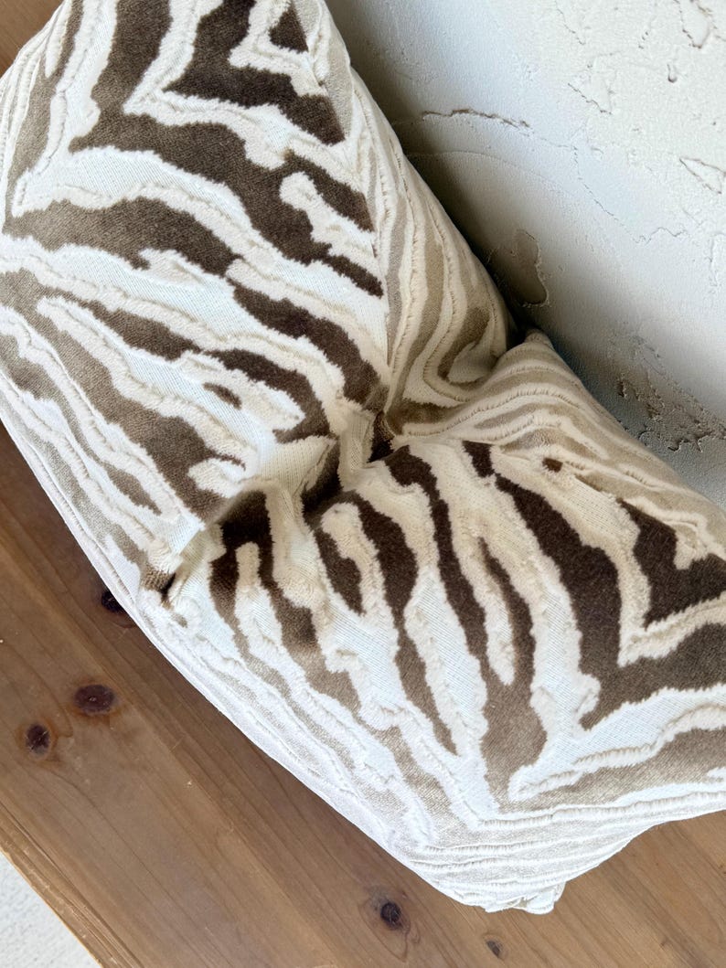 May include: A brown and white zebra patterned throw pillow. The pillow is made of a soft, plush fabric.