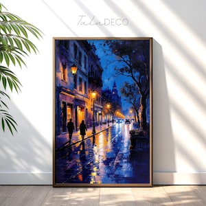 May include: A framed watercolor painting depicts a European street scene at night. The artwork features a wet, reflective street with streetlights illuminating the buildings and two figures walking. The color palette is dominated by blues and oranges.