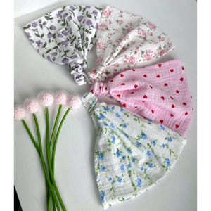 Può includere: Quattro fasce per capelli in tessuto con retro elasticizzato, caratterizzate da vari motivi tra cui fiori viola, piccole stampe floreali rosa, cuori rossi su sfondo rosa chiaro e fiori blu su bianco, insieme a cinque fiori decorativi rosa.