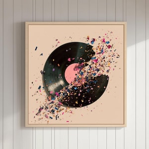 Op de afbeelding: Een ingelijst kunstwerk met een zwarte vinylplaat die lijkt te exploderen in kleurrijke fragmenten. De plaat heeft een roze label in het midden. Het kunstwerk wordt getoond op een lichtbeige achtergrond, in een licht houten frame.