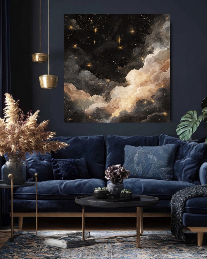K&ouml;nnte beinhalten: Ein gro&szlig;er, quadratischer Leinwanddruck zeigt eine Nachthimmel-Szene mit dunklen Wolken, goldenen Sternen und einem weichen, leuchtenden Licht. Das Kunstwerk h&auml;ngt &uuml;ber einem marineblauen Samtsofa mit dekorativen Kissen. Der Raum ist mit goldenen Akzenten dekoriert.