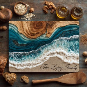 Puede incluir: Tabla de cortar rectangular de madera con un diseño oceánico en capas en tonos azules, blancos y beige. La tabla presenta una escena de playa con el texto "The Lopez Family" en escritura elegante. Rodeada de cuencos de madera, nueces y botellas de aceite.