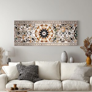 Op de afbeelding: Een lang, rechthoekig wandkunstwerk met een gedetailleerd moza&iuml;ekontwerp. Het moza&iuml;ek heeft een centraal cirkelvormig patroon met bruine, zwarte en witte elementen, omgeven door bloem- en geometrische vormen. Het kunstwerk is omlijst met een decoratieve rand.