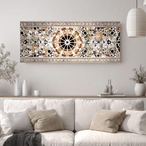 Op de afbeelding: Een rechthoekig kunstwerk voor aan de muur met een moza&iuml;ekontwerp. Het kunstwerk heeft een centraal cirkelvormig patroon met een zwart centrum en uitstralende bruine en witte segmenten. De rand is lichtbeige met ingewikkelde details. Het is gemonteerd boven een witte bank.