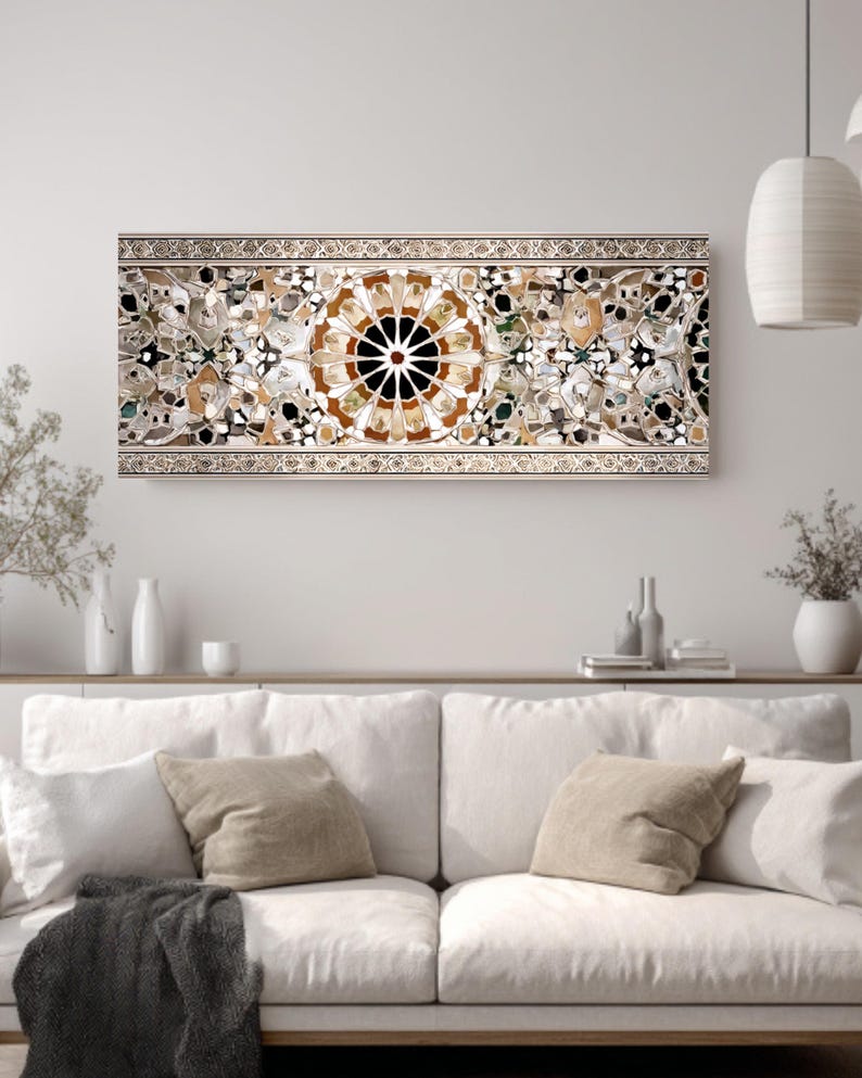 Op de afbeelding: Een rechthoekig kunstwerk voor aan de muur met een moza&iuml;ekontwerp. Het kunstwerk heeft een centraal cirkelvormig patroon met een zwart centrum en uitstralende bruine en witte segmenten. De rand is lichtbeige met ingewikkelde details. Het is gemonteerd boven een witte bank.