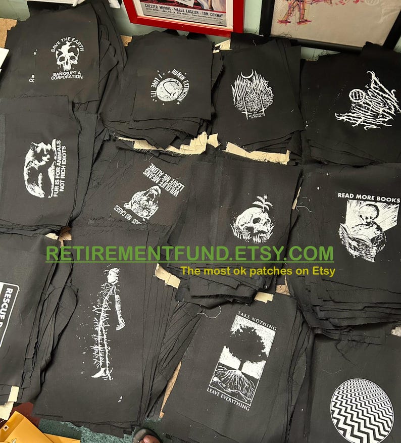 Może przedstawiać: Kolekcja czarnych łat z tkaniny z białymi wzorami. Łaty przedstawiają r&oacute;żne hasła i obrazy, w tym "Ratuj Ziemię", "Zostaw mnie w spokoju", "Czytaj więcej książek" i "Nie bierz nic, zostaw wszystko".