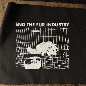 Puede incluir: Parche blanco y negro con el texto "END THE FUR INDUSTRY" y un gráfico de un animal pequeño en una jaula.
