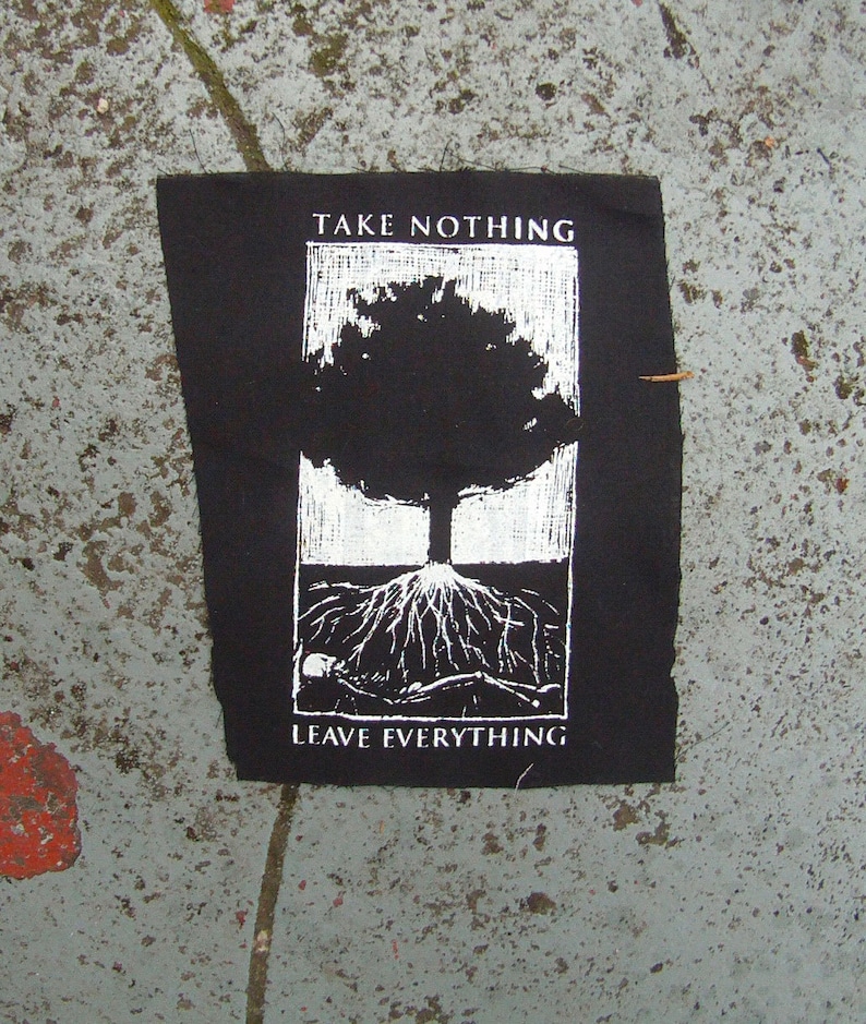 May include: Black patch with a white illustration of a tree and its roots. The text "TAKE NOTHING" is above the tree, and "LEAVE EVERYTHING" is below. The patch is rectangular with slightly frayed edges.
