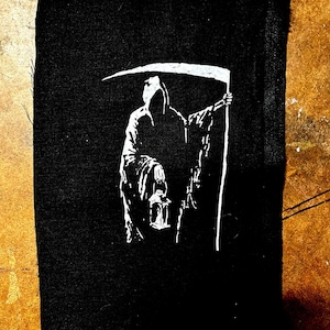 May include: Black and white embroidered patch of the Grim Reaper holding a lantern and a scythe.